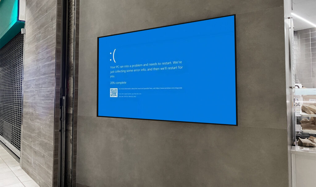 A wall in the street, with a screen with a blue screen system failure.